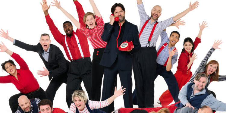 A photo of the cast of Showstopper! They are wearing red blue black and white clothing and are waving their hands in the air