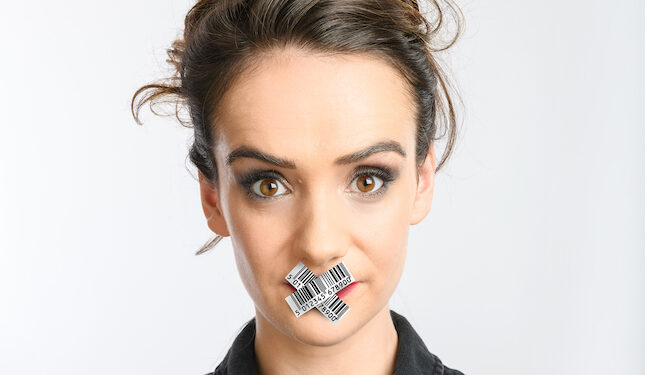 A photo of comedian Gabby Killick, she has her dark hair in an undo and has silver tape in a cross over her mouth