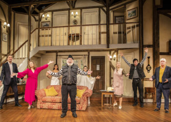 The cast of noises off stand on set