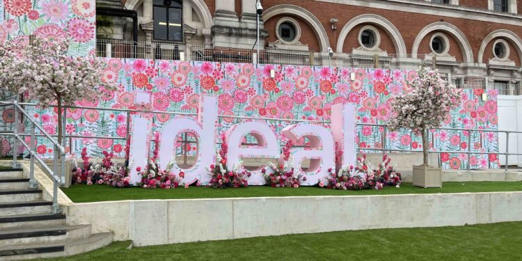 The entrance bto The Ideal Home show 2024, the word ideal in big pink letters adorned with flowers is next to the stairs and there is a floral backdrop behind it