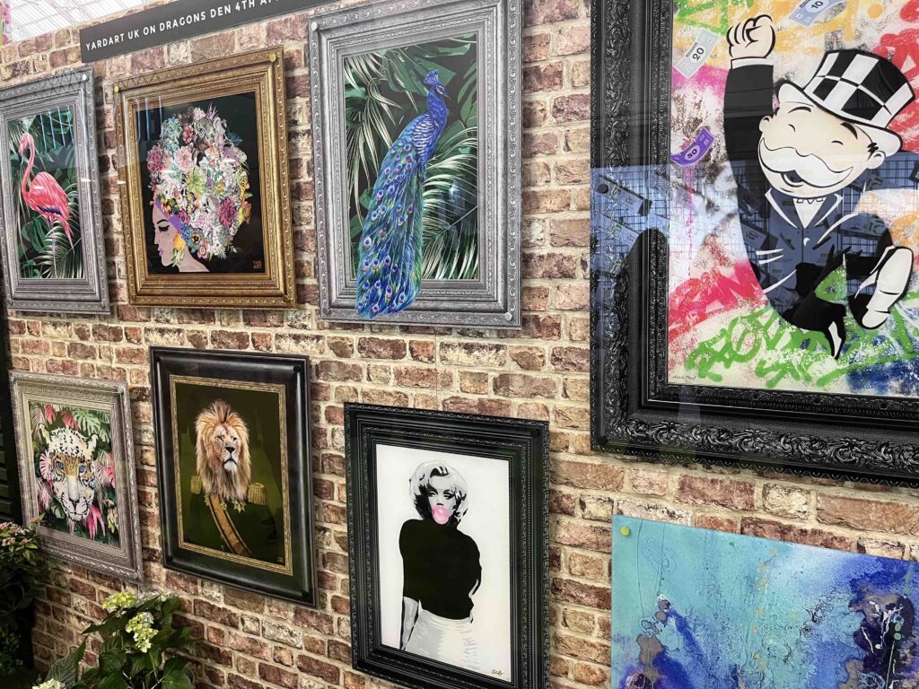 Yard Art's stand at The Ideal Home Show, it shows a faux brick wall with the art displayed on it 