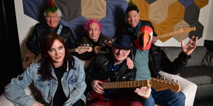 The band Beldon Haigh are posing for a promo shot on a sofa they are a 6 piece band and 3 of them are wearing masks of people and one is wearing a mask of a parrot