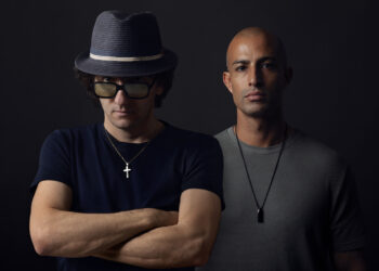 Shyam P and Moon Rocket are stood against a black backdrop and are both looking in to the camera