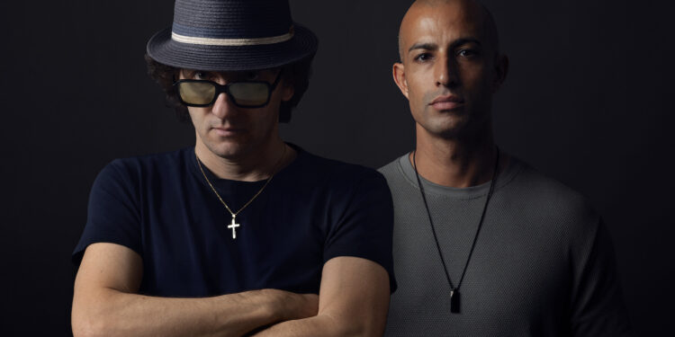 Shyam P and Moon Rocket are stood against a black backdrop and are both looking in to the camera