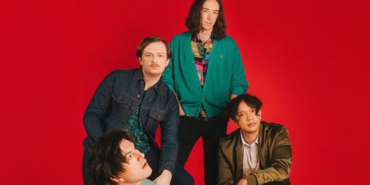 The band Hotel Mira pose infant of a red background