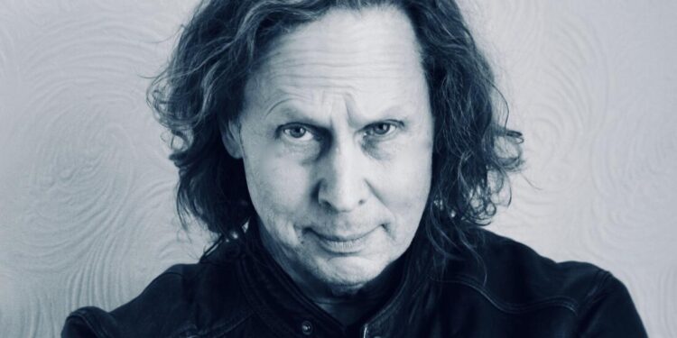 Konrad Kinard stars into camera in a black and white shot, wearing a leather jacket
