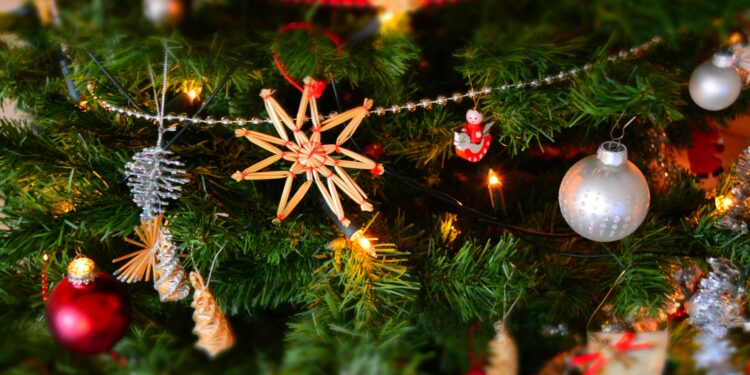 Close-up of a decorated Christmas tree with fairy lights, red and silver baubles, and traditional straw star ornaments