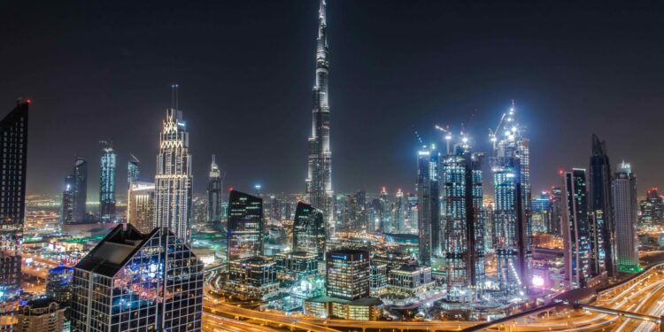 Dubai skyline at night with the Burj Khalifa towering above illuminated skyscrapers and highways.