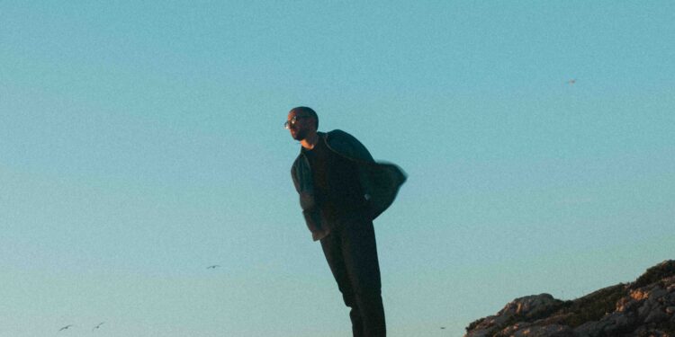 Olivier Casassus standing on rocky cliffs at sunset beneath a clear blue sky.